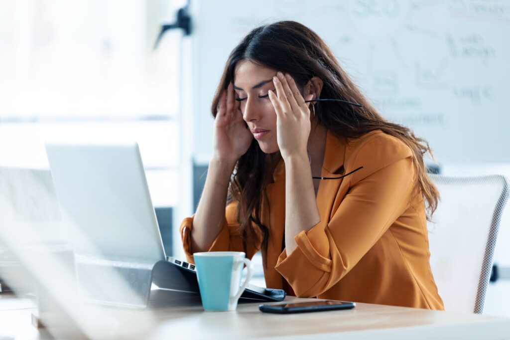 Business young woman with headache working with laptop in the office.