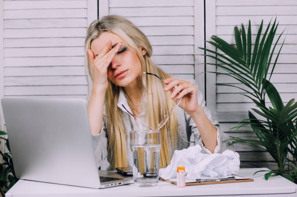 Stressed business woman working from home on laptop and having headache
